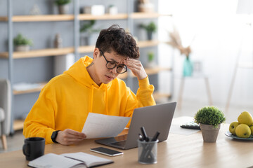 Asian man holding paper reading report working on pc