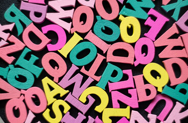 Colored letters of the English alphabet on a black table. Learning to read