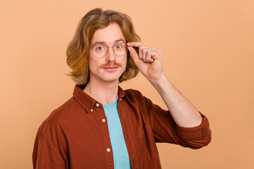Portrait of attractive intelligent content skilled red-haired guy touching specs isolate over beige...