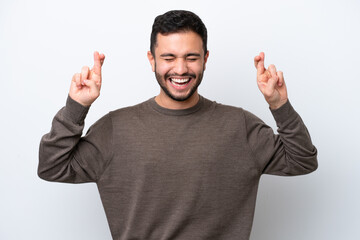 Young Brazilian man isolated on white background with fingers crossing