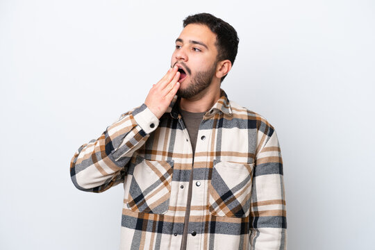 Young Brazilian man isolated on white background yawning and covering wide open mouth with hand