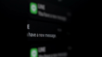 Close up, Blurred, Icon, text message notification on a smartphone lock screen, black background.
