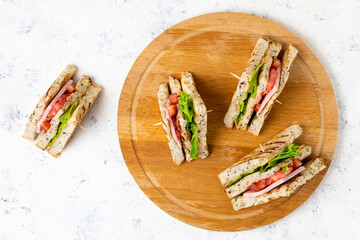 sandwich with ham cheese tomatoes lettuce onions on cutting board. Classic club sandwich with whole...