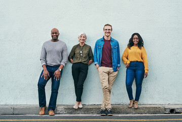 Nothing can stand in our way. Full length shot of a group of businesspeople standing in line against a wall outdoors.