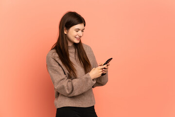 Naklejka premium Young Ukrainian girl isolated on pink background sending a message or email with the mobile