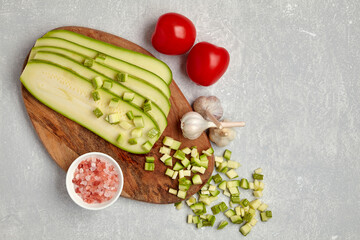 Sliced ​​zucchini on a wooden cutting board, tomatoes, garlic and pink salt