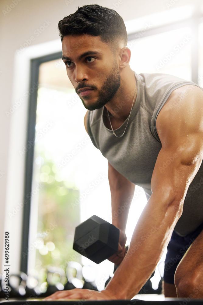 Poster life has ups and downs, we call them reps. shot of a young man working out with dumbbells in a gym.