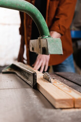 Fototapeta na wymiar cropped view of carpenter cutting board on circular saw in woodwork studio.