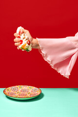 Female hand squeezes sweet cake isolated bright red background. Contemporary artwork. Vintage,...