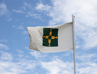 Brasilia flag hoisted. Blue sky with clouds, strong wind. Order and progress, legibly in the center. Fabric a little worn due to age.