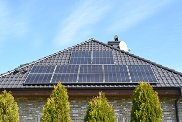Solar panels on the roof of a new home against a blue sky.