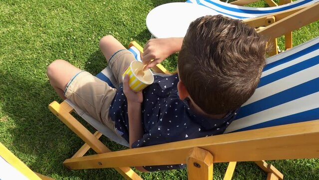 A young boy eating ice cream then turns to see if anyone is watching.