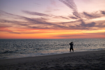 Man fishing during sunset on the beach