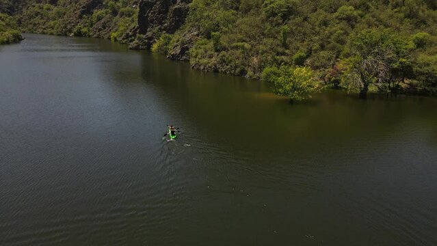 Aerial view of couple kayaking on wild River surrounded by green jungle of South America during sunlight