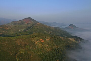 the fog sea cover valley with an aerial view and green hill ranger at dawn