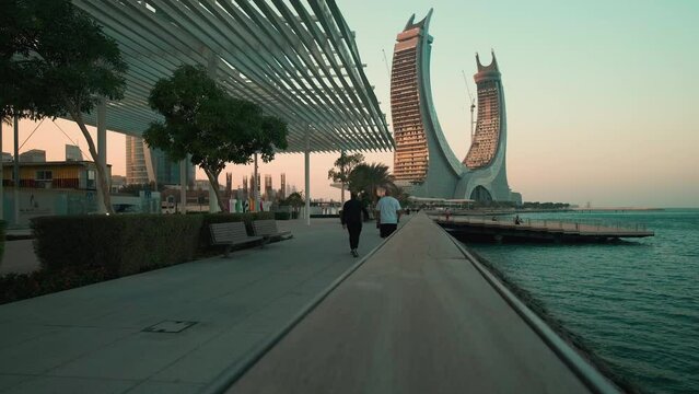 Lusail Corniche at the marina in Lusail, Qatar sunset shot showing fountain, people walking on the promenade with skyline in background