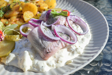 Fresh matjes or soused herring on an apple cream sauce, traditional fish dish with onions, fried...