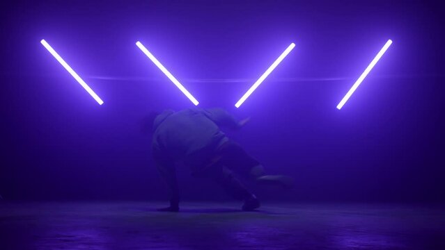 Agile breakdancer performing dance on nightclub. Young man making spinning moves
