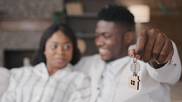 Blurred unfocused view African American married couple newlyweds wife and husband holding keys to new house rented apartment happy with real estate. Girlfriend and boyfriend satisfied living together
