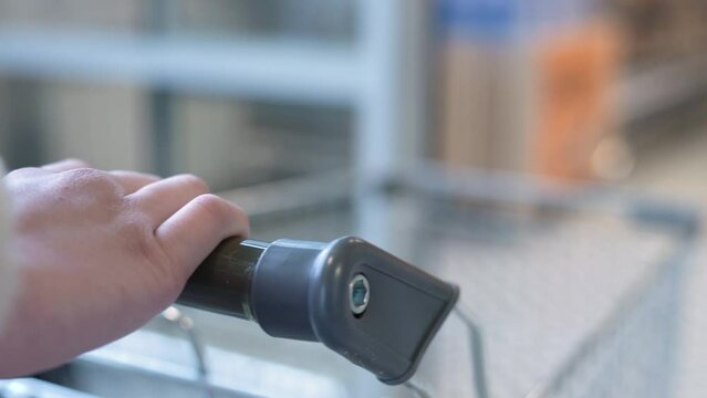 The cart pulls into the store. A girl walks into a supermarket with an empty cart. self-sliding doors