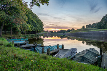 Fototapeta na wymiar row boats docked with a beautiful sunset at the moat at historical Naarden-Vesting, Naarden, Holland, The netherlands, stock photo
