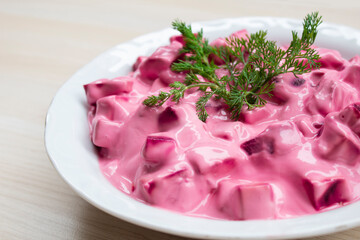 Beet salad made with yogurt on wooden background