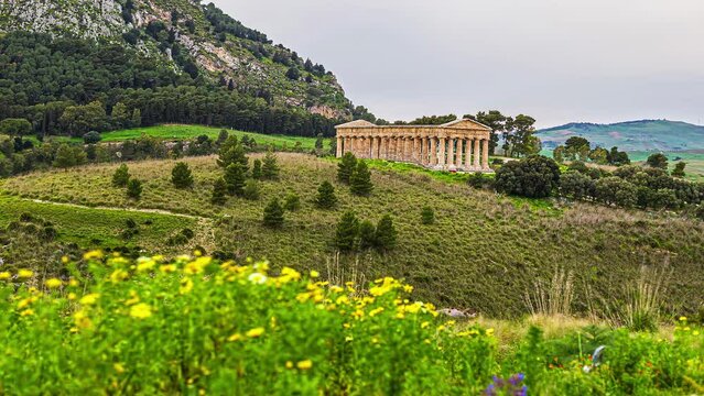 Static view to the Doric temple of Segesta, Province of Trapani, Sicily, Italy at daytime in timelapse in rural countryside over hilly terrain.