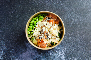 Top view of wok box, bowl of rice on background. Rice fried and stirred with salmon, avocado, onion, cucumber, broccoli, sesame. Chinese, Asian food delivery. Packaging for woks. 