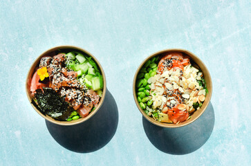 Top view of wok box, bowl of rice on background. Rice fried and stirred with salmon, avocado, onion, cucumber, broccoli, sesame. Chinese, Asian food delivery. Packaging for woks. 