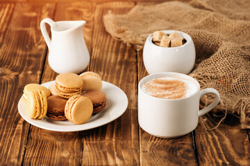Obraz premium cup of coffee, milk, sugar and macaroons on wooden background
