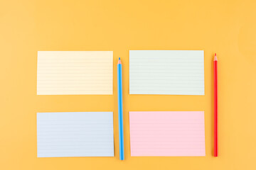 four blank writing papers and pencils  on a yellow background. space for text.