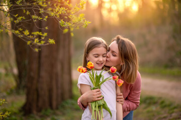 happy mothers day. child , daughter congratulates mother and gives a bouquet of flowers to tulips.