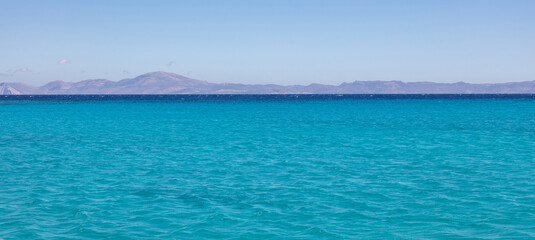 Fototapeta na wymiar Koufonisia island, Cyclades, Greece. Panoramic view from Aegean ripple sea of rocky landscape. Banner