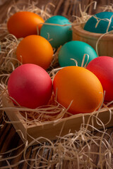 Colorful easter eggs on hay. Bright and colorful eggs on wooden background