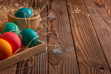 Colorful easter eggs on hay. Bright and colorful eggs on wooden background. Copyspase
