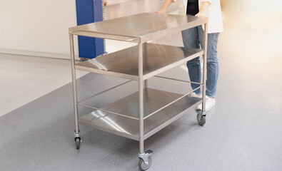 Female hand pushing the stainless steel food trolley cart to the move a lot parcel.