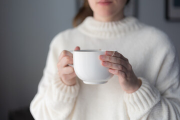 woman's hands holding a big white cup of hot tea
