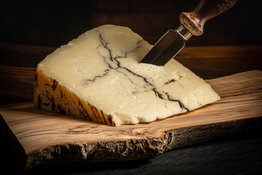 Italian Sheep Milk Cheese with Black Truffle Veining on a Wood Board
