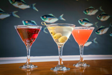 Three Cocktails in front of a Fish Background on a Wooden Table