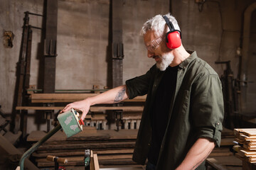 side view of middle aged woodworker pushing button on control relay in workshop.