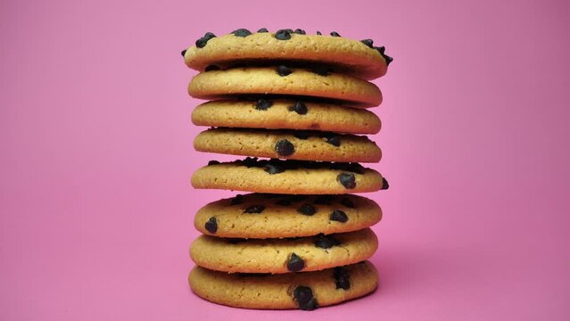 A stack of chocolate chip cookies sprouting on a pink background. American Cookies