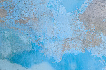 Old flaky wall with destroyed plaster. Renovation of old house. Industrial style design wall background. Grunge cracked concrete wall with old paint. Shabby peeling old background