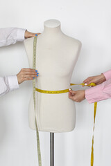 Anonymous Fashion Designers Working With ruler and Mannequin In White Studio