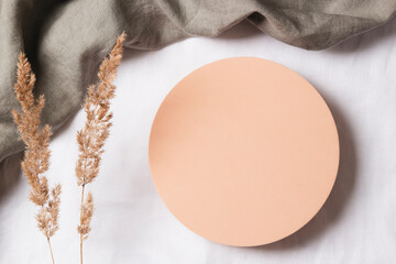 Blank pastel round platform podium for cosmetics or products and dry grass plant on natural linen...