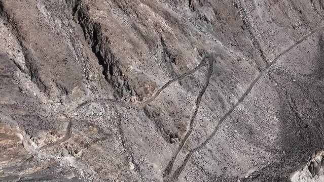 Aerial View Of Winding Old Silk Road Through Rugged Arid Mountains In Pakistan. Zoom In