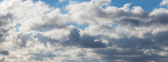 Obraz premium Picturesque blue sky with white and gray fluffy clouds in sunny weather