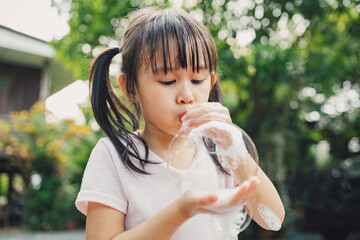 little girl blowing soap bubbles with hands. Family lifestyle, outdood activities, summer holidays with kidsat home.