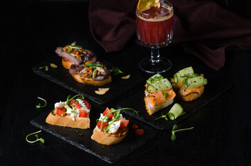 A set of three different types of bruschetta. Bruschetta with roast beef, salmon and cucumber, tomatoes, feta and pesto sauce.