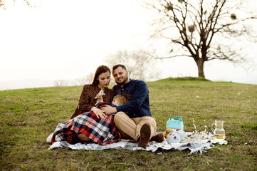 outdoor recreation of a young married couple with a small child and a pregnant wife. the family is...