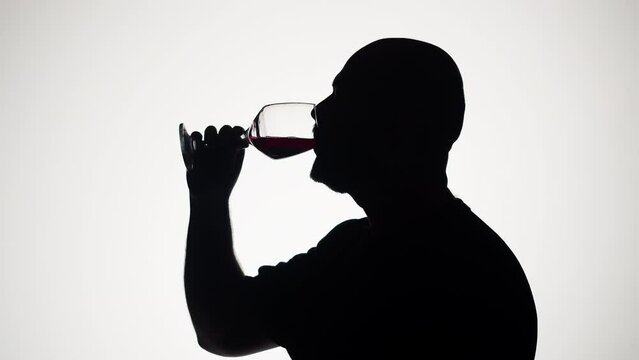 Man drinking wine on white background. Shadow silhouette of male person celebrating holiday in bar. Romantic evening. 